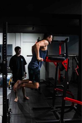 Male athlete performing dips with personal trainer supervision in a boutique gym, focusing on triceps and chest development in Singapore.