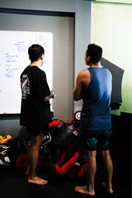 Client and personal trainer discussing workout plans and strategies in a gym in Singapore, highlighting professional collaboration and gym use.