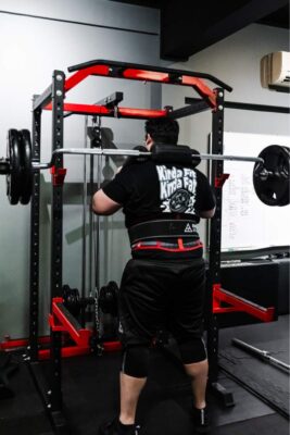 Man performing heavy squats at a boutique gym in Singapore, showcasing intense strength training under careful supervision.
